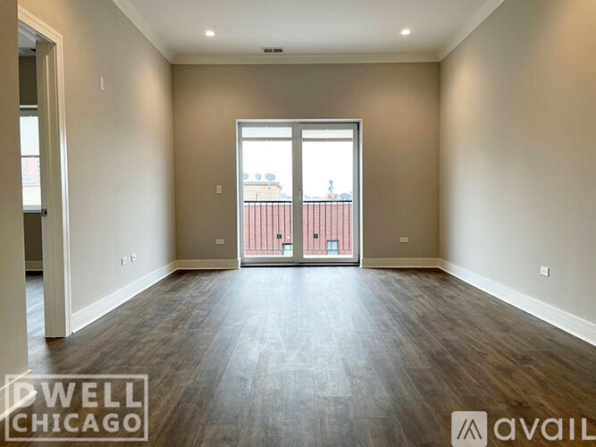 A spacious room with a view of a balcony through a sliding glass door.