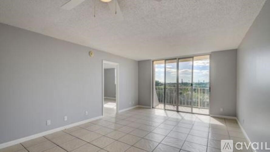 A spacious room with a sliding glass door leading to a balcony.