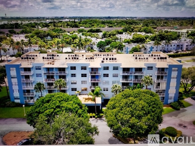 A large blue and white apartment building with trees in front.