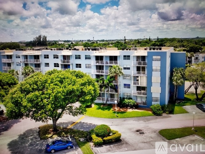 A blue car is parked in a parking lot in front of a building.