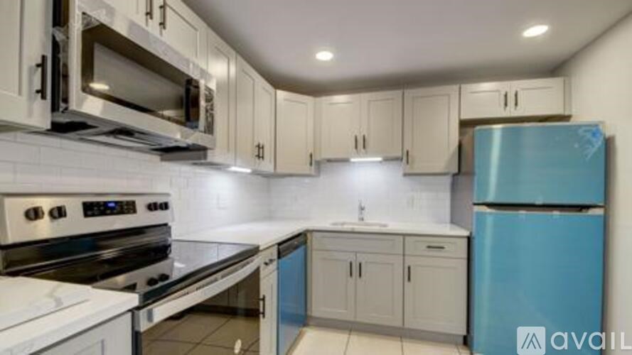 A kitchen with a blue fridge and white cabinets.