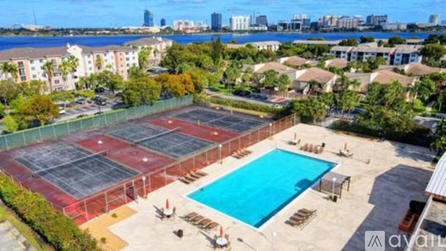 A tennis court with a pool and apartment buildings in the background.