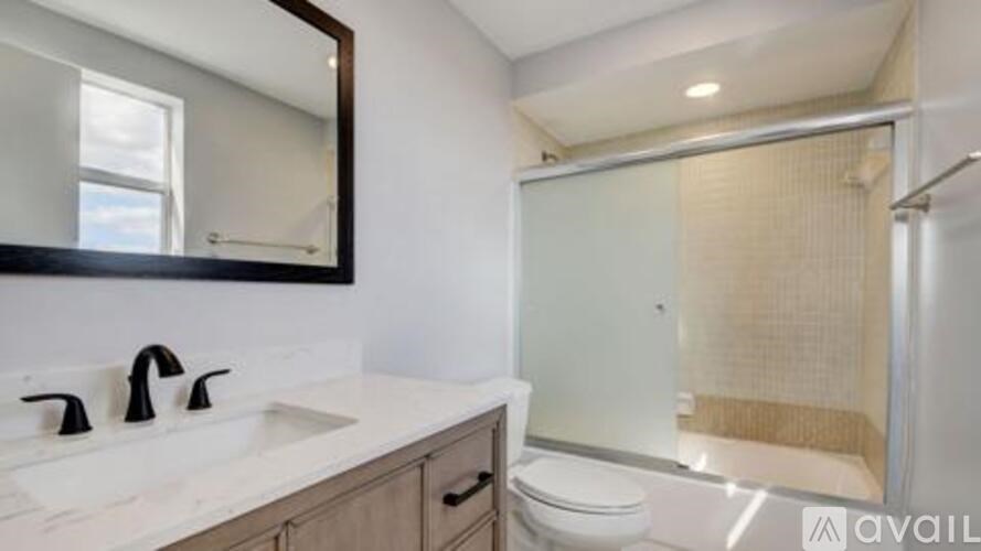 A bathroom with a sink, mirror, and shower.