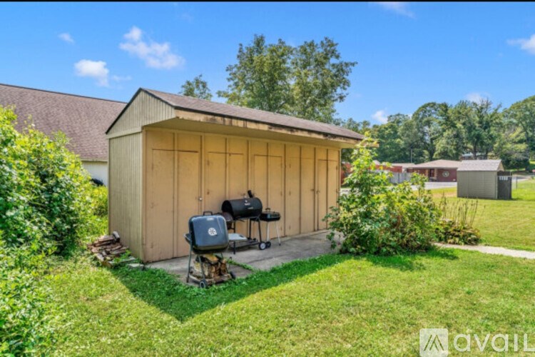 A small wooden shed with a grill in front of it.