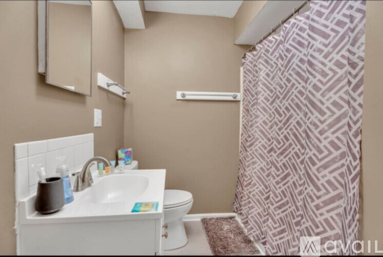 A bathroom with a white sink and a shower curtain with a geometric pattern.