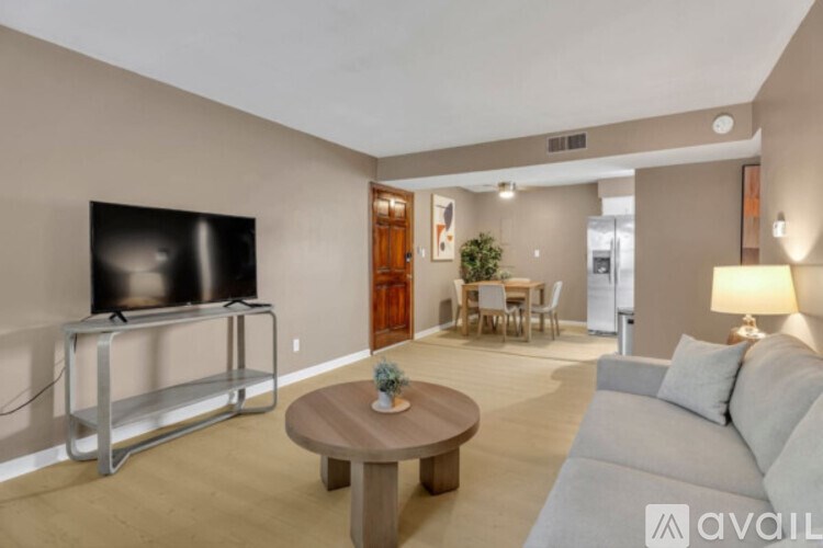 A living room with a television, a couch, a coffee table, and a dining table.