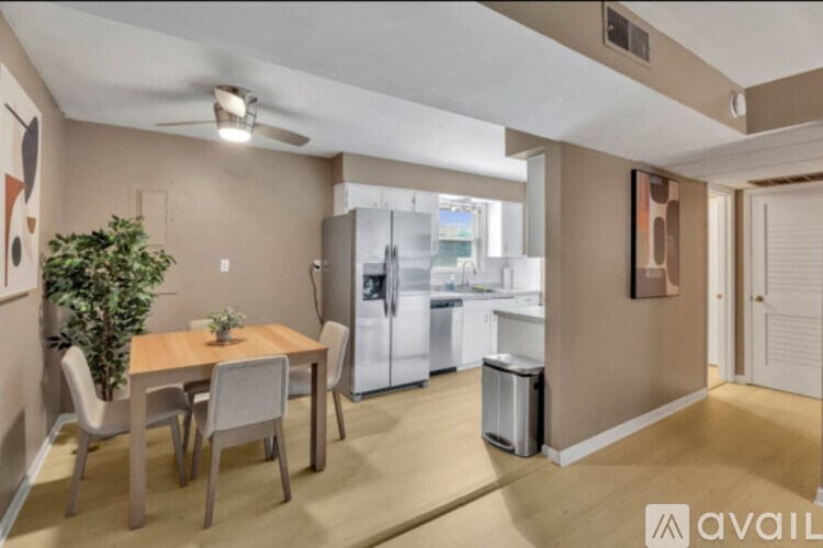 A kitchen with a table and chairs in the foreground and a refrigerator in the background.