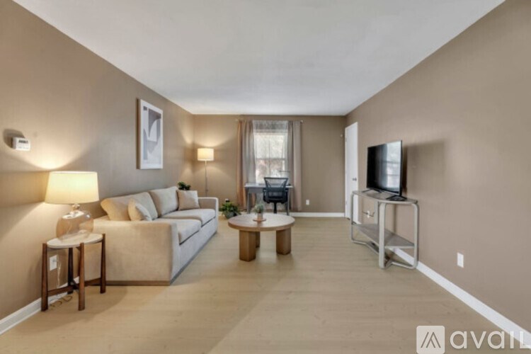 A living room with a white couch, a coffee table, and a television.