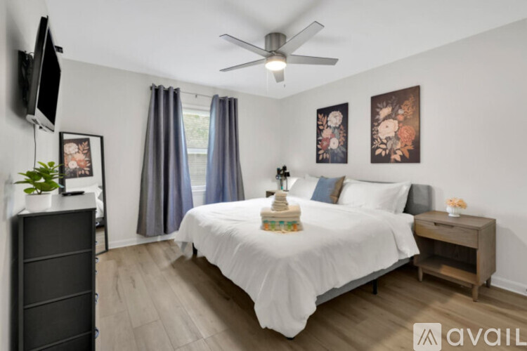 A bedroom with a bed, a dresser, a ceiling fan, and a window with curtains.