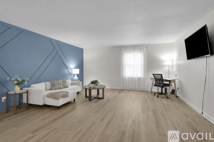 A living room with a white couch, a chair, a small table, and a television.