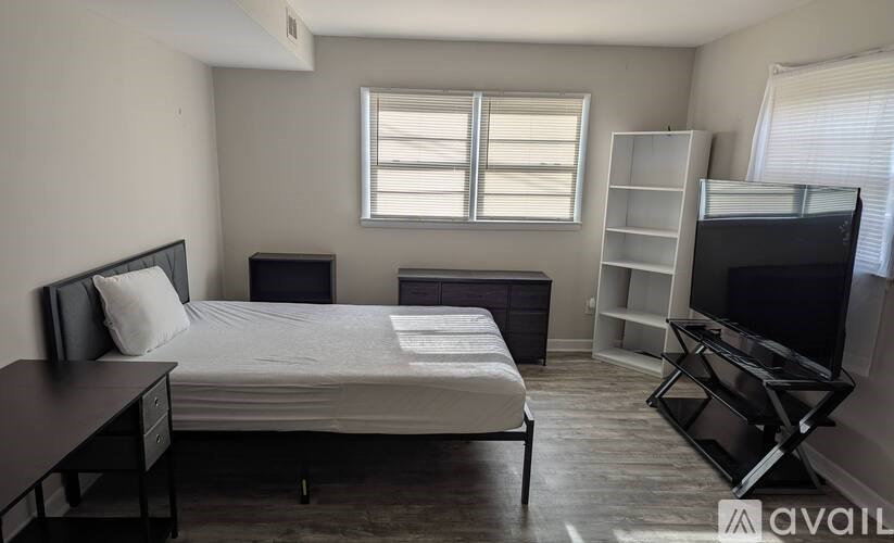 A bedroom with a bed, desk, and television.