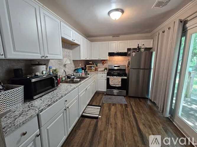 A kitchen with white cabinets and a wooden floor.