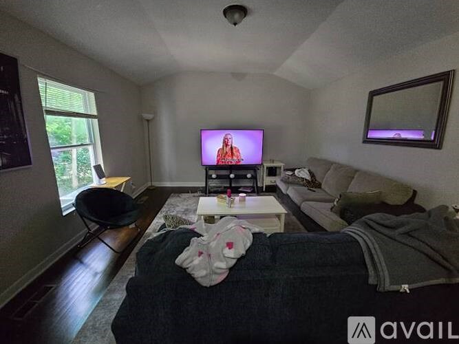 A living room with a television on, a couch and a chair.