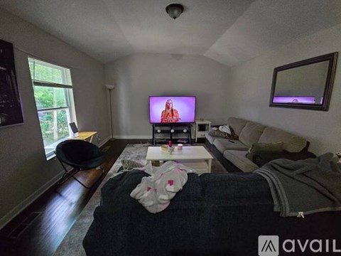 A living room with a television on, a couch and a chair.