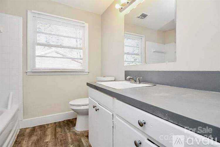 A bathroom with a toilet, sink, and mirror.