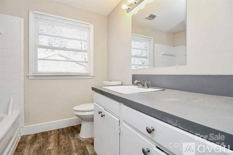A bathroom with a toilet, sink, and mirror.