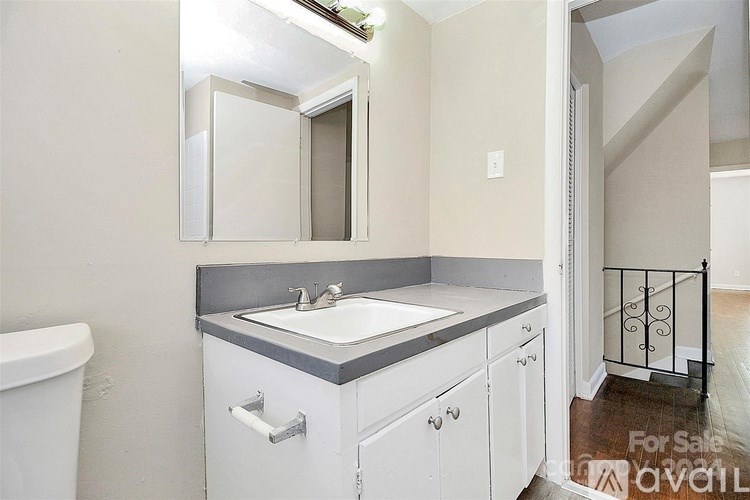 A bathroom with a sink, mirror, and toilet.