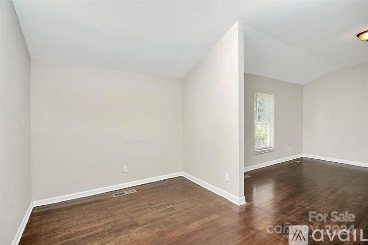 Empty room with wood flooring and white walls.