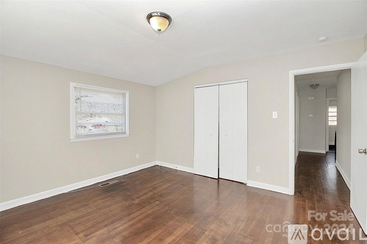 A room with wood flooring and a white door is for sale.