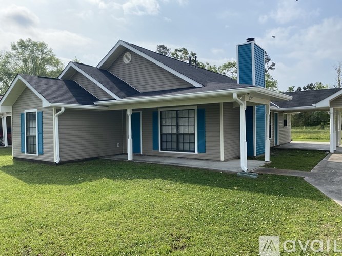 A house with a grey roof and blue trim is for sale.