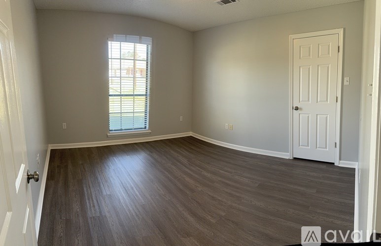A room with a wooden floor and a window with blinds.