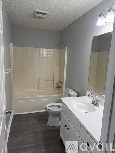 A bathroom with a toilet, sink, and mirror.