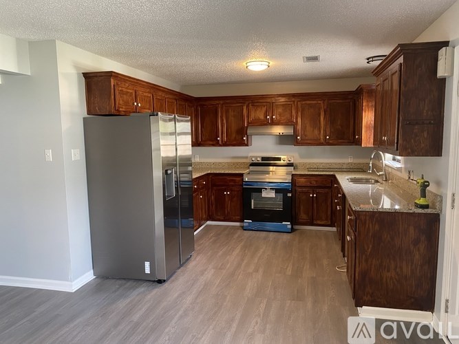 A kitchen with wooden cabinets and a grey fridge.
