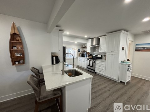 A modern kitchen with white cabinets and a wooden floor.