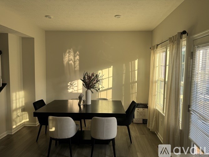 A dining room with a black table and white chairs.