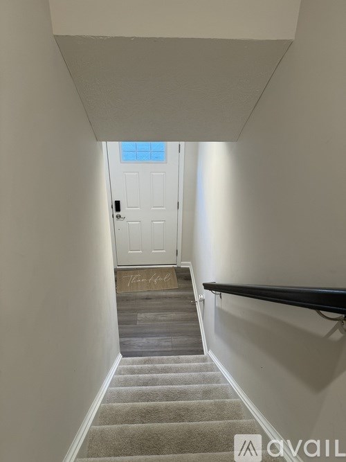 A hallway with a staircase leading to a door at the end.