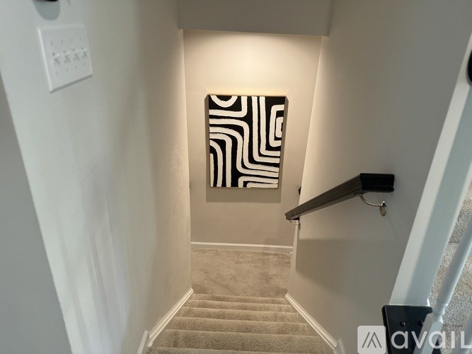 A hallway with a carpeted staircase and a painting on the wall.