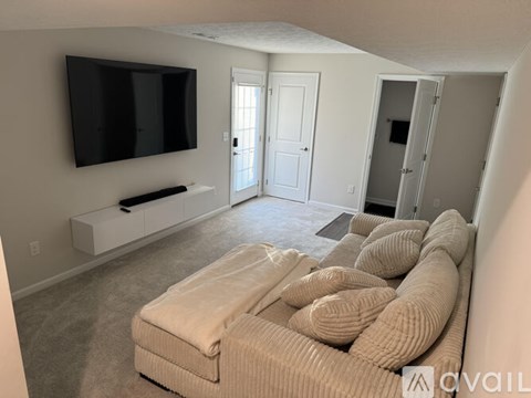 A living room with a large couch and a television mounted on the wall.