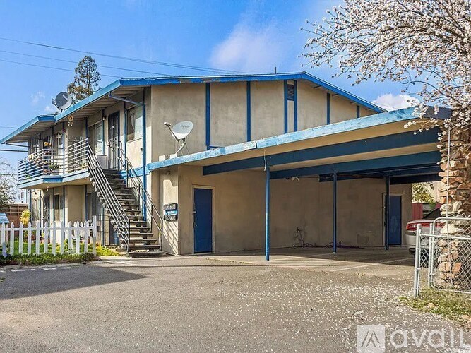 A two-story building with a blue door and a satellite dish on the roof.
