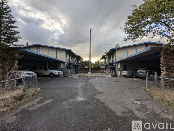 A parking lot with two garages and a car parked in front of each.