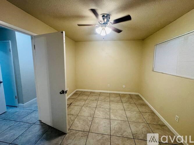 A room with a ceiling fan and tile flooring.