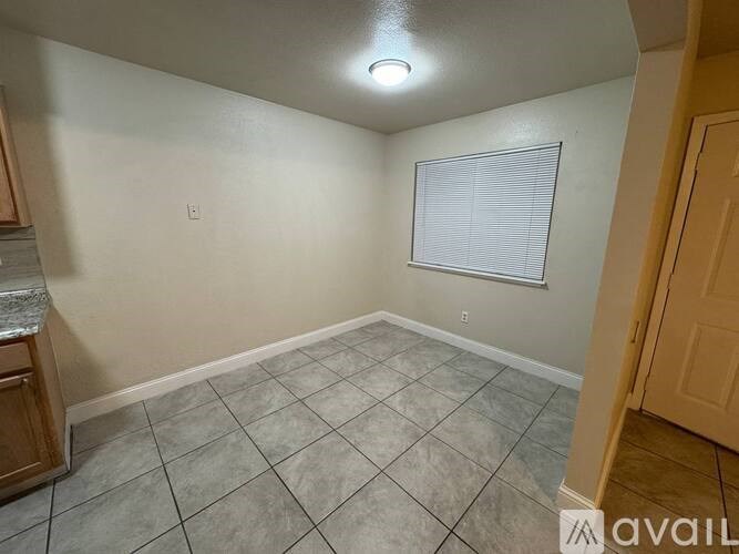 A room with a tiled floor and a window with blinds.