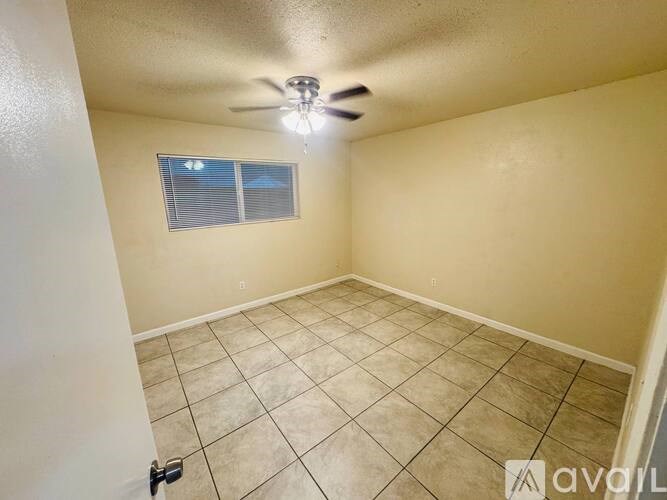 A room with a ceiling fan and a window with blinds.