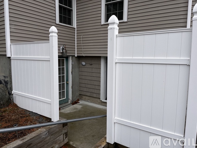 A white fence in front of a grey house.
