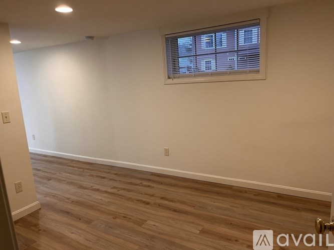 A room with wooden flooring and a window with blinds.