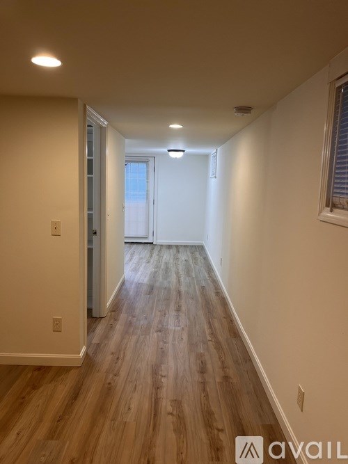 A long hallway with wood floors and white walls.