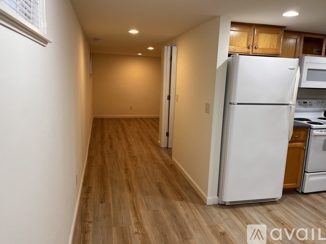 A kitchen with a white refrigerator and wooden floors.