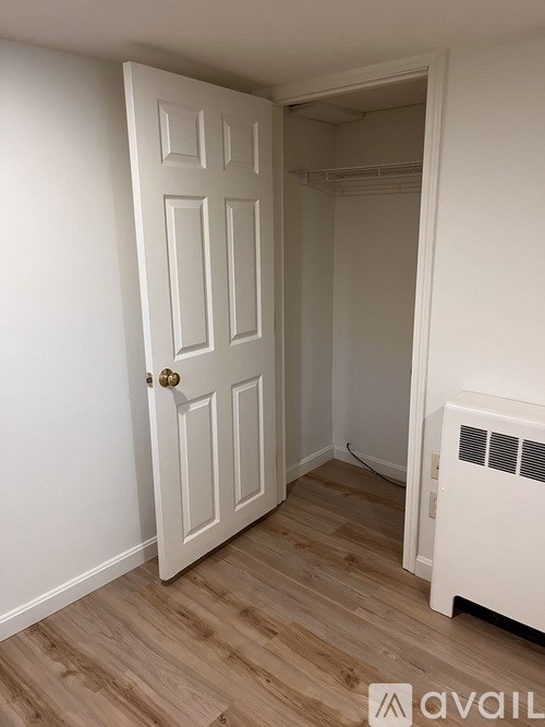 A white door with a gold handle is in a room with a wood floor.