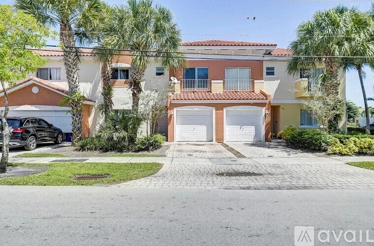 A house with a driveway and palm trees in front.