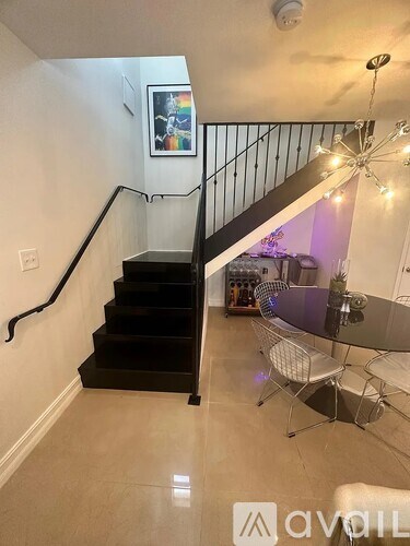 A black staircase with a white railing and a glass table with chairs.