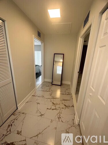 A hallway with marble flooring and white walls.