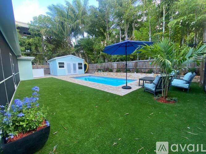 A backyard with a pool and a blue umbrella.