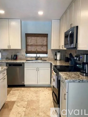 A kitchen with white cabinets and a granite countertop.