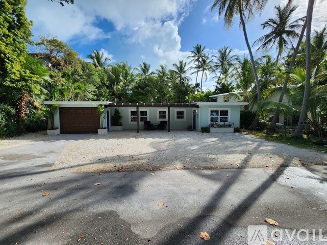 A house with a driveway in front of it surrounded by trees.