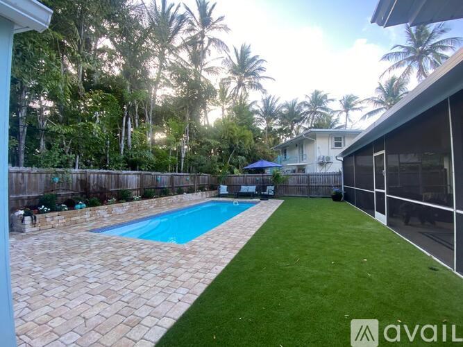 A pool surrounded by a stone border and a green lawn.