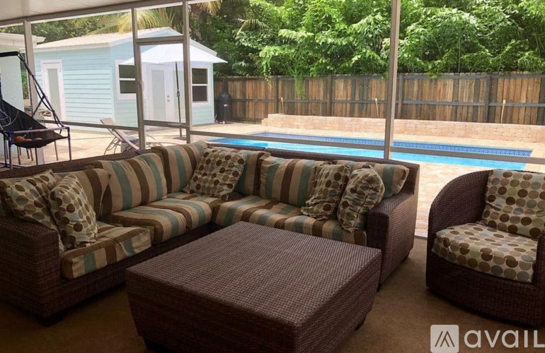 A poolside patio with a striped couch and matching chair.